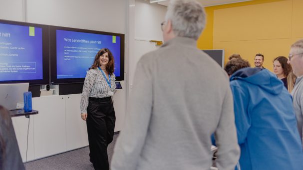 Eine Präsentation in einem modernen Raum mit einer Referentin und Zuhörern.